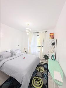 a white bedroom with a bed and a green chair at Kitusuru staycation in Wabuga