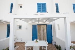 uma casa branca com portas azuis e uma mesa branca em Residence Blu Mare em San Vito lo Capo