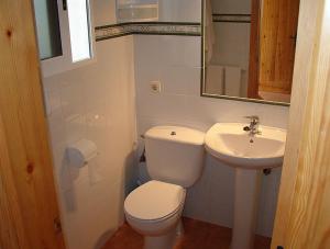 a white bathroom with a toilet and a sink at Hostal Las Acacias in Los Caños de Meca