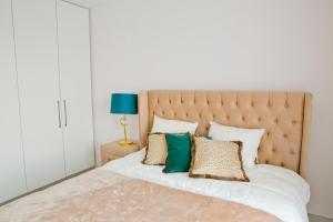 a bedroom with a large bed with green and gold pillows at Elegant City Center Apartment 7A in Krakow