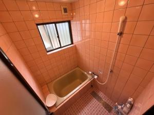 ein Badezimmer mit Badewanne und Fenster in der Unterkunft MaruHouse in Nachikatsuura + 20 Fotos