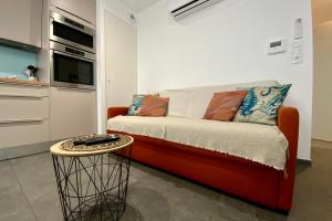 an orange couch in a kitchen with a table at Villa Marie 2 Appartement tout confort climatisé 1 chambre proche plage in Le Grau-du-Roi