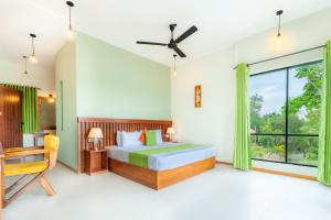 a bedroom with a bed and a large window at River Shades Hotel in Hikkaduwa