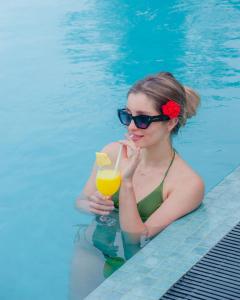a woman in a swimming pool holding a drink at River Shades Hotel in Hikkaduwa