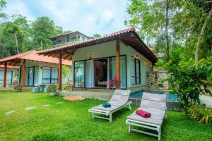 a house with two lounge chairs in the yard at River Shades Hotel in Hikkaduwa