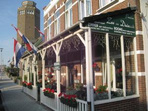 Une rangée de boutiques dans une rue avec une tour d'horloge dans l'établissement Pension Zee en Duinzicht, à Zandvoort