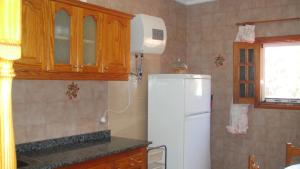 a kitchen with a white refrigerator and a window at Casa El Pino in Mogán