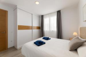 a bedroom with a white bed with blue towels on it at Merlin 14 V1 in Playa Honda