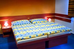 Cama grande con sábanas y almohadas azules y amarillas en Penzion Bowling, en Liptovský Mikuláš