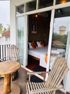 a room with a bed and chairs on a porch at Negombo Green Palace in Negombo
