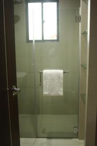 ducha con puerta de cristal y toalla en Kew Hotel Tagbilaran en Tagbilaran City