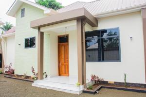 a small white house with a brown door at KiliView Homestay in Moshi