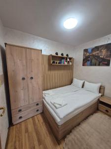 a small bedroom with a bed and a cabinet at Апартаменти Ванкови in Veliko Tŭrnovo
