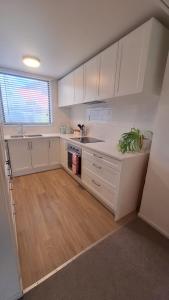a kitchen with white cabinets and a wooden floor at Relax on Robertson in Queenstown