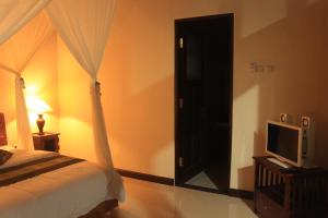 a bedroom with a bed and a door with a television at Alit Bali Villa in Canggu