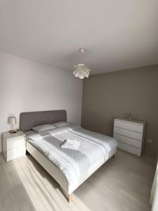 a white bedroom with a bed and a night stand at B&B Unicat in Bistriţa +10 photos