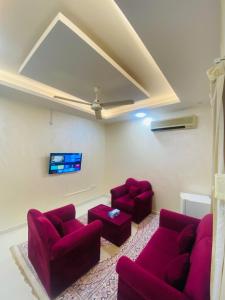 a living room with two red couches and a tv at AL FANAR REST HOUSE LLC in Ras al Khaimah