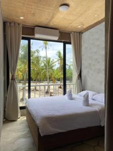 a bedroom with a large bed and a large window at Ohayo Siargao in General Luna