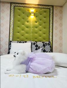 a white dog laying on top of a bed at 하이얀모텔 in Hwach'ŏl-li