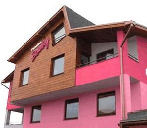 um edifício cor-de-rosa com um restaurante em cima em Penzion Bowling em Liptovský Mikuláš