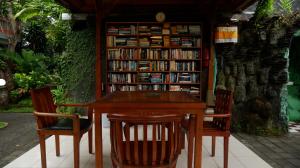 a table and two chairs and a book shelf with books at Swastika Bungalows in Sanur