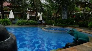 a statue of a frog sitting next to a swimming pool at Swastika Bungalows in Sanur