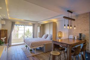 a bedroom with a bed and a table and a kitchen at WIlson Palace - Studio avec terrasse et climatisation in Antibes