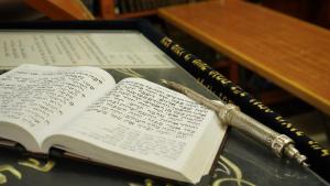an open book with a pen on a table at Aristocrat Hotel Glatt Kosher in Bene Beraq