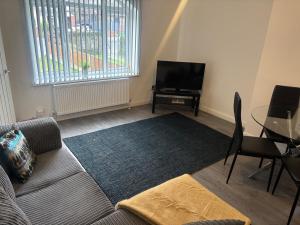 a living room with a couch and a tv and a table at 3 Bed-Sleeps 5- Garden-Pets-Parking in Wolverhampton