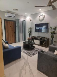 a living room with a blue couch and a tv at Esthelixapartment in Madina