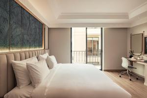 a bedroom with a large white bed with a desk at Lumi Hội An Hotel in Hoi An