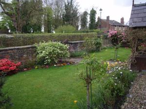 a garden with flowers and a brick wall at Church End Farm Bed and Breakfast in Hale