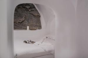 a white room with a bed and a window at Iliovasilema Hotel & Suites in Imerovigli