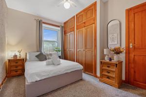 a bedroom with a bed and a dresser and a window at Ramsay Lane in Lossiemouth