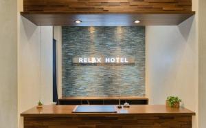 a reception desk in a hotel with a brick wall at Relax Hotel Takayama Station in Takayama