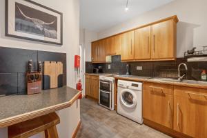 a kitchen with wooden cabinets and a washer and dryer at Ramsay Lane in Lossiemouth