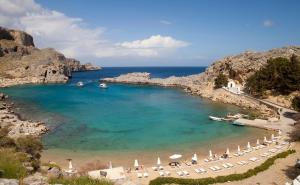 a beach with chairs and umbrellas in the water at Lindos Villa Estelle in Líndos
