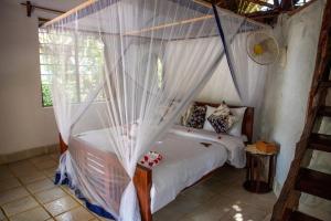 a bedroom with a canopy bed with white curtains at VeriDiana Hotel Zanzibar in Dimbani +203 photos