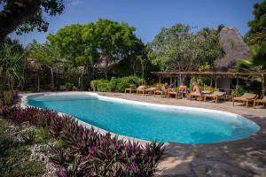 a pool at a resort with people sitting on chairs at VeriDiana Hotel Zanzibar in Dimbani