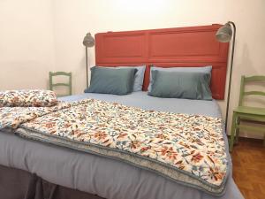 a large bed with a red headboard and two chairs at Da Anny - Valdilana in Coggiola