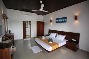 a bedroom with a large bed with a ceiling fan at Hideaway Lodge in Tangalle