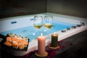 two candles and two glasses of wine next to a bath tub at Premiere Luxury Catania in Catania
