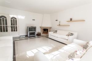 uma sala de estar com mobiliário branco e uma lareira em Casa Bordalo - Family, Beach, Culture and Surf nas Caldas da Rainha