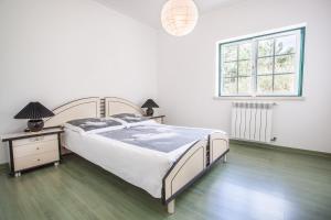 Un dormitorio blanco con una cama grande y una ventana en Casa Bordalo - Family, Beach, Culture and Surf, en Caldas da Rainha