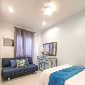 a bedroom with a bed and a blue couch at Natos Residences - Gonzaga in Bacolod