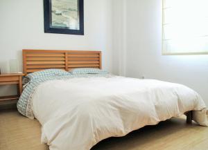 a bedroom with a large bed with a wooden headboard at Atico Alhamilla in Almería