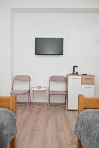 a room with two chairs and a table and a tv at Sobe i apartmani MILLA in Slavonski Brod