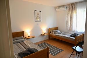 a bedroom with two beds and two chairs and a window at Sobe i apartmani MILLA in Slavonski Brod
