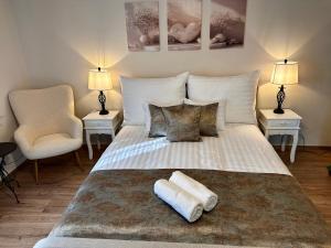 a bedroom with a large white bed with two chairs at Petőfi Sarok Apartman in Keszthely