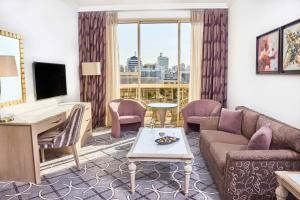 a living room with a couch and a desk at Gefinor Rotana – Beirut in Beirut